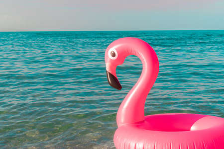 Sea background. Pink inflatable flamingo in blue ocean water for sea summer beach background. Luxury lifestyle travelの写真素材