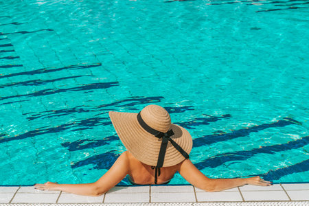 Summer fun. Happy young sexy girl in bikini swimsuit, sunglasses and straw hat relaxing in blue pool...