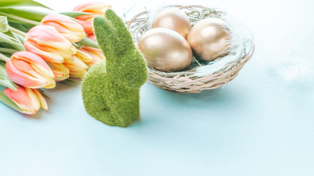 Easter Golden eggs in basket with spring tulips, white feathers on pastel blue background in Happy...