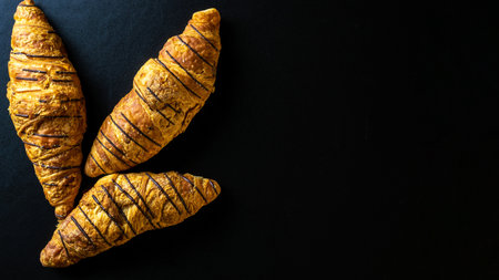 Croissant basket. Freshly baked bread or french pastry croissants with jam on black bakery table. Tasty croissants with copy space, flat layの写真素材