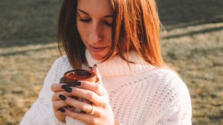 Tea drinking woman. Happy young girl with cup of coffee in sun sitting outdoor. Cup of Hot Beverageの写真素材