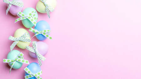 Easter banner. Colorful egg with tape ribbon on pastel pink background in Happy Easter decoration. Foil minimalist egg design, modern top view templateの写真素材