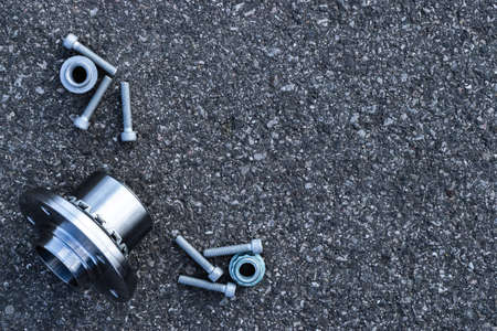 Vehicle parts. Auto motor mechanic spare or automotive piece on dark road asphalt background. Tarmac dark gray grainy road. Technology of mechanical gearの写真素材