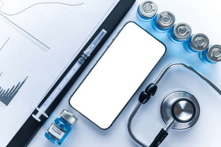 Medical equipment. Doctor stethoscope, healthcare charts, syringe with needle and black smartphone with blank screen on hospital equipment background. For design application, website projectの写真素材