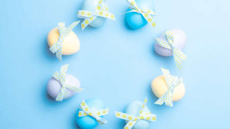 Easter card. Colorful egg with tape ribbon on pastel blue background in Happy Easter decoration. Flat lay, top view with copy spaceの写真素材