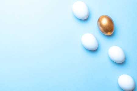 Easter pattern. Golden, white color egg on pastel blue background in Happy Easter decoration. Spring holiday top view conceptの写真素材