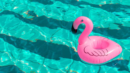Pink pool. Pink inflatable flamingo in pool water for summer beach background. Pool float partyの写真素材