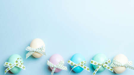 Easter flat. Colorful egg with tape ribbon on pastel blue background in Happy Easter decoration. Spring holiday top view conceptの写真素材