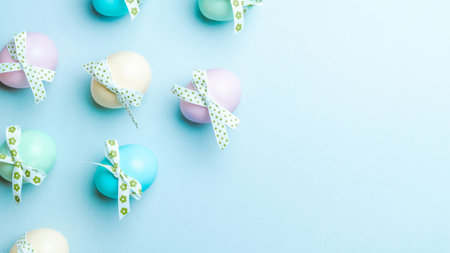 Easter flat. Colorful egg with tape ribbon on pastel blue background in Happy Easter decoration....