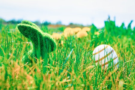 Easter basket. Golden egg with yellow spring flowers in celebration basket on green grass...