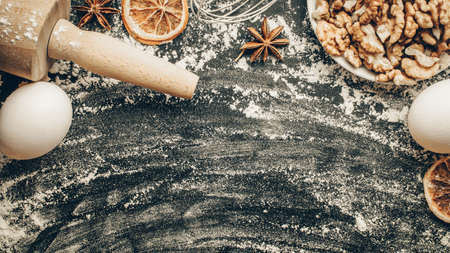 Baker bread. Fresh food ingredients: flour, eggs, nut and star anise, orange on black chalkboard background for bread. Free space for text. Top viewの写真素材