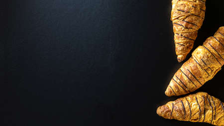 Croissant basket. Freshly baked bread or french pastry croissants with jam on black bakery table. Tasty croissants with copy space, flat layの写真素材