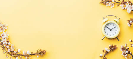 Summer time. Spring blossom and April floral nature with alarm clock on yellow background. Beautiful scene with blooming tree. Easter Sunny day. Orchard abstract blurred background. Springtimeの写真素材