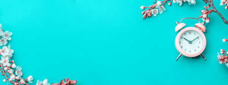 Sakura flower, spring blossom and April floral nature with alarm clock on blue background. Banner for 8 march, Happy Easter with place for text. Springtime concept for greeting cards with copy spaceの写真素材