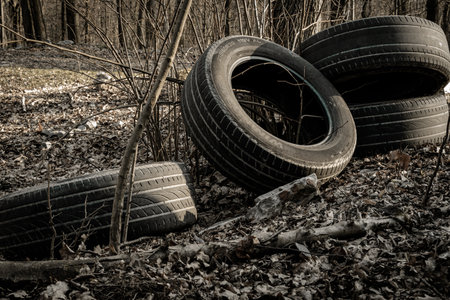 Environmental pollution. Waste rubbish tire in forest. Plastic garbage trash in woodland. Ecological problem with Empty used dirty plastic bottlesの写真素材