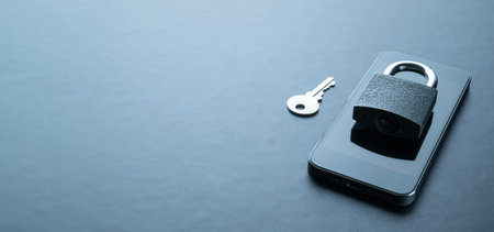 Internet protection. Modern space gray mobile phone with padlock, key on dark background. Darkweb, darknet and hacking conceptの写真素材