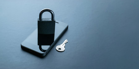 Business security protection. Modern space gray mobile phone with padlock, key on dark background. Smartphone fraud, online scam and cyber security threatの写真素材