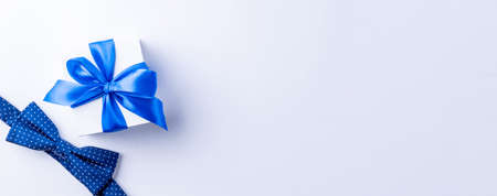 Gift dad. Blue bowtie or tie, white box with bow ribbon on light background. Happy loving family and Fathers Day conceptの写真素材