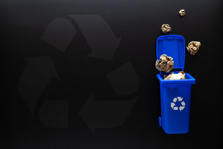 Recycle paper garbage. Blue dustbin for recycle paper trash on black background. Bin container for...