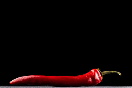 Red hot peppers. Spicy chile cayenne pepper isolated. Red hot chili paprika on black background. Fresh spice vegetable conceptの写真素材