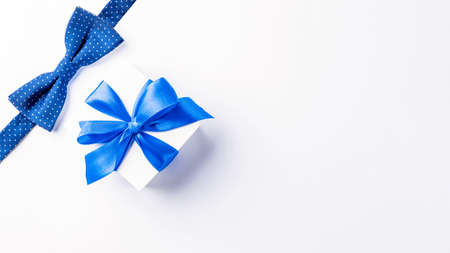 Fathers gift. White box with bow ribbon, blue bowtie or tie on light background. Concept of Fathers Day greeting card, copy space for textの写真素材
