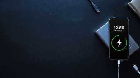 Power bank smartphone. Mobile phone or smartphone battery charging from portable powerbank with white usb cable. Modern technology concept in top viewの写真素材