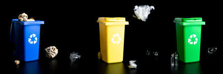 Recycling set bins. Yellow, green, blue dustbin for recycle plastic, paper and glass can trash isolated on black background. Container for disposal garbage waste and save environmentの写真素材