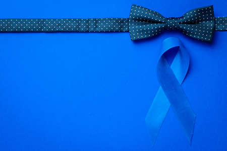Cancer awareness blue. Blue ribbon, fashion bowtie isolated on deep blue background. Awareness prostate cancer of men health in November. November and International Mens Dayの写真素材