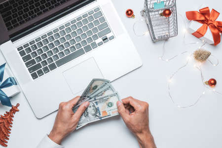 Xmas online shopping. Gift box red ribbon, trolley and laptop, dollar in flat lay internet shopping...