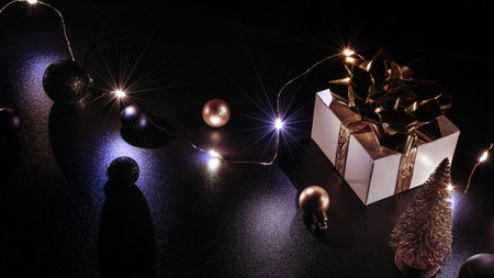 Gift boxes background. White gift box with golden ribbon, New Year balls and sparkling lights...