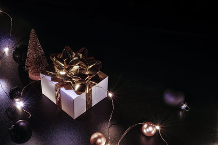Gift boxes background. White gift box with golden ribbon, New Year balls and sparkling lights...