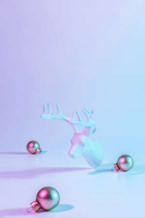 Christmas deer neon winter background. Minimal abstract xmas reindeer. Holiday decoration bauble ball on neon gradient backdrop. Minimal new year cardの写真素材