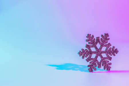 Neon Christmas winter background. Minimal abstract xmas snowflake. Holiday decoration snow on night pink gradient. Happy new year copy spaceの写真素材