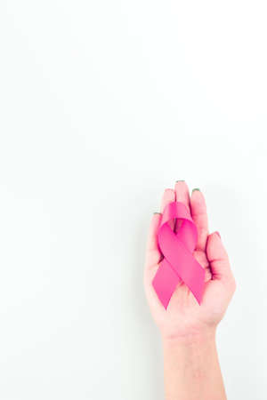Cancer ribbon. Woman hands holding health care symbol pink ribbon on white background. Breast cancer support concept. World cancer dayの写真素材