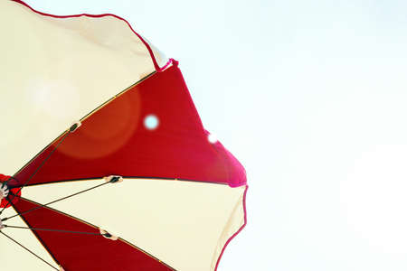 Umbrella beach. Red summer beach parasol on blue sea background. Sun sunshade for vacation travel. Outdoor relax holiday at ocean with copy spaceの写真素材