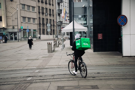KATOWICE. POLAND - March 26, 2021: Food courier bag for delivery takeaway service. Driver man on bike or motorcycle for fast restaurant deliver. Uber eats express food delivery serviceのeditorial素材