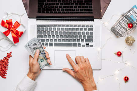 Online gift. Gift box red ribbon for Christmas, trolley and laptop in flat lay internet online shopping composition. Xmas sales and discounts promotionsの写真素材