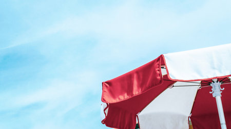 Umbrella beach. Red summer beach parasol on blue sea background. Sun sunshade for vacation travel. Outdoor relax holiday at ocean with copy spaceの写真素材