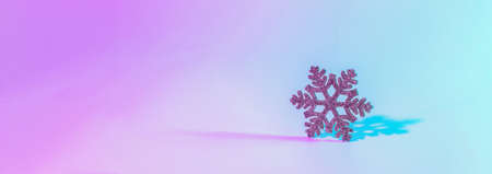 Neon Christmas winter background. Minimal abstract xmas snowflake. Holiday decoration snow on night pink gradient. Happy new year copy spaceの写真素材