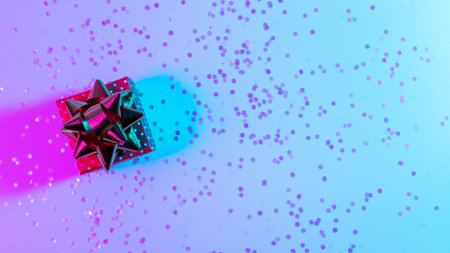 Christmas composition neon. Xmas gift box with shine lights. Holiday decoration on neon abstract gradient backdrop. New year bannerの写真素材