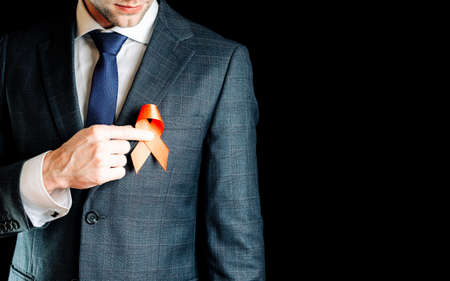 His support. Red ribbon in hiv world day in man hand. Awareness aids and cancer symbol isolated on black background. World aids day conceptの写真素材