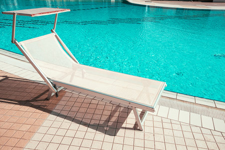 Resort pool. Summer resort chair, relax lounge at luxury hotel pool. Beach lounger chaise. Vacation sunbed. Blue water, sunny happy travel holidayの写真素材
