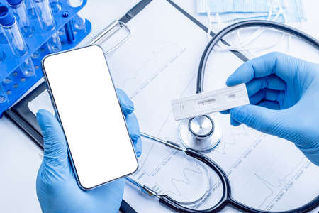 medical application. Hospital equipment: doctor stethoscope, healthcare charts, syringe with needle and black smartphone with blank screen. Mockup generic deviceの写真素材