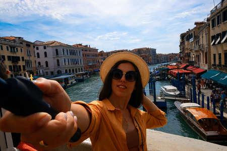 Travel influencers Venice island. Paint building house in Europe Venezia city. Photographer blogger girl with smartphone in Venice San Marco square. Traveling and freelancing, modern lifestyleの写真素材