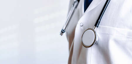 Stethoscope background. Happy doctor in hospital wearing scrubs, blue gloves, provide checkup, examine patient in clinic. Medical service, consultation or education, healthy lifestyle conceptの写真素材