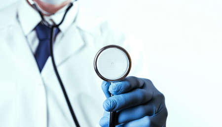 Stethoscope background. Happy doctor in hospital wearing scrubs, blue gloves, provide checkup, examine patient in clinic. Medical service, consultation or education, healthy lifestyle conceptの写真素材