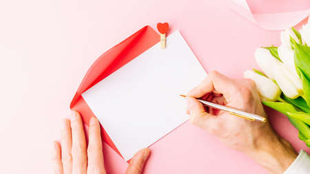 mothers day background. Spring white tulip flower, gift box with red ribbon on flat lay pink background. Top view wedding love minimal conceptの写真素材