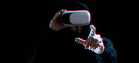 Vr goggles virtual reality blurred. Young man in digital helmet for 3d virtual reality game on dark background. Study and virtual world in 3D simulation with glitch effectの写真素材