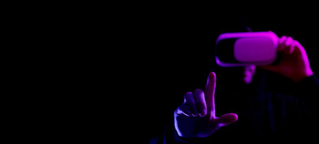 Virtual reality game vr. Young man in digital glasses for virtual reality technology isolated on dark neon background. Study and virtual world in 3D simulationの写真素材