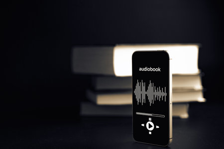 Audiobook concept. Smartphone screen with audiobook application on paper books black background. Concept of education, library, studentsの写真素材